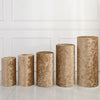 A row of four cylindrical gold fabric covers displayed against a white paneled wall.