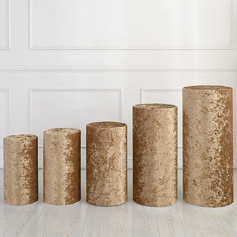 A row of four cylindrical gold fabric covers displayed against a white paneled wall.