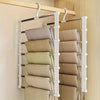 A white foldable multi-layer pants hanger with stainless steel rods displaying folded beige and olive green pants.