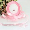 Pink silk satin ribbon rolled on a spool with a white center core