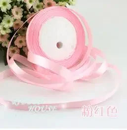 Pink silk satin ribbon rolled on a spool with a white center core