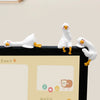 A white resin cartoon duck figurine standing on a black surface.