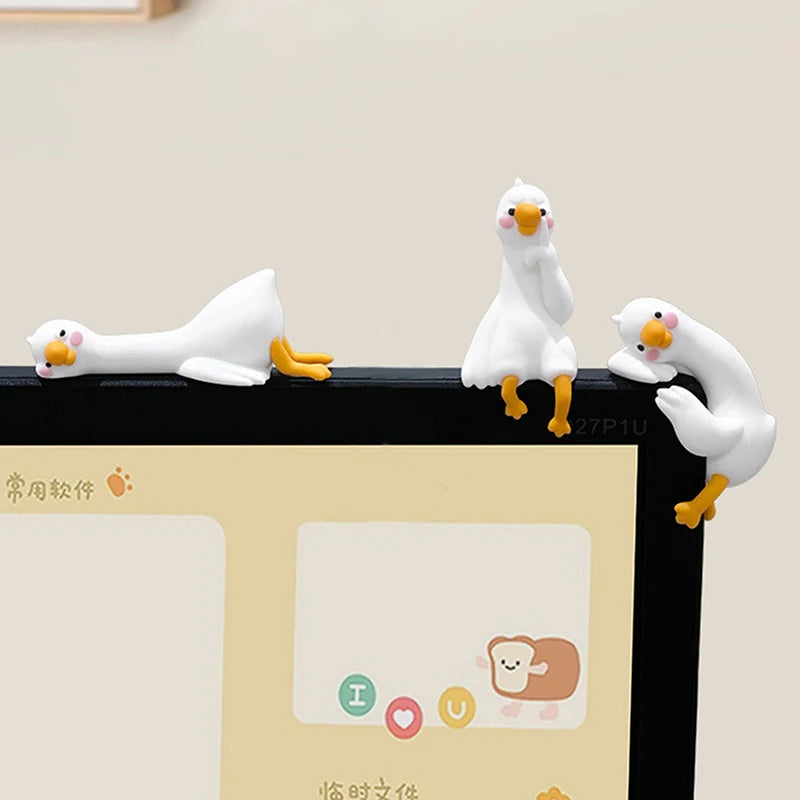 A white resin cartoon duck figurine standing on a black surface.