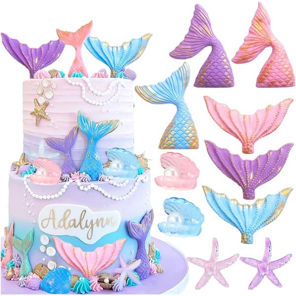 A tiered cake decorated with purple and pink mermaid tail toppers, seashells, and starfish.