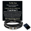 Black braided leather cuff bracelet with a silver clasp and a engraved message on a dark background.