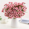 A bouquet of pink silk gerbera daisy artificial flowers in a white ceramic vase.