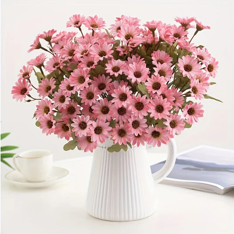 A bouquet of pink silk gerbera daisy artificial flowers in a white ceramic vase.