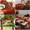 A close-up of a rustic wooden table set for a meal with a terracotta runner, glassware, and cutlery.