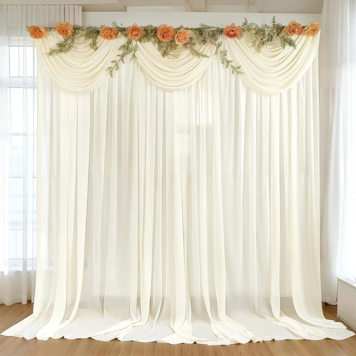 A sheer cream chiffon backdrop curtain with floral greenery draped for wedding or event decor.