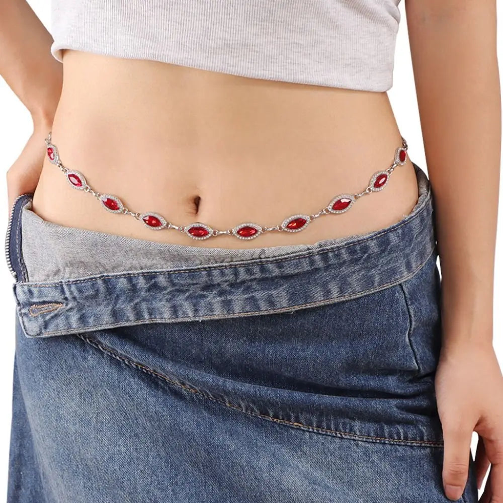 A woman wearing a denim skirt and light top displays a delicate red crystal waist chain.