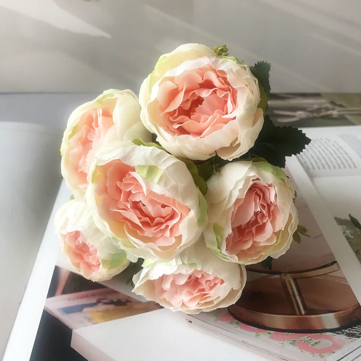 A bouquet of artificial silk roses and peonies in soft pink and cream colors.
