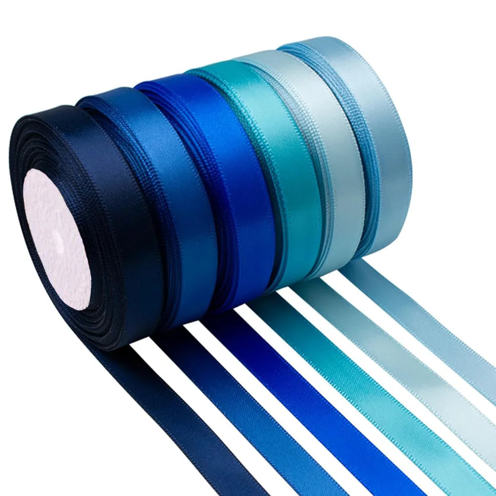 A roll of satin silk ribbon in various shades of blue and teal, with several ribbons unwound below.
