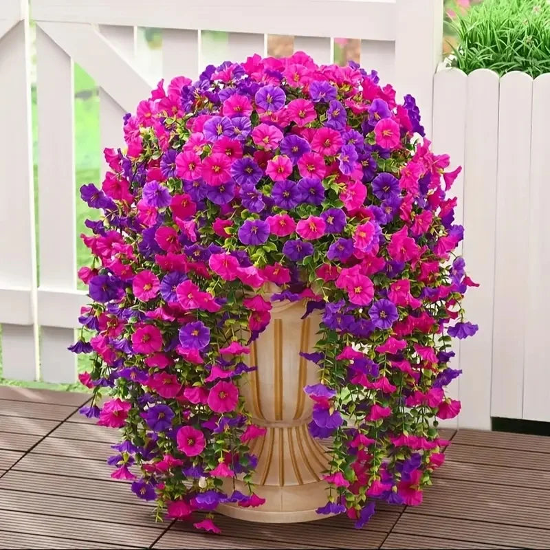 A vibrant display of artificial morning glory hanging vines in shades of pink and purple, arranged around a light-colored ped