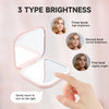 A pink portable folding makeup mirror with an LED light showing three brightness levels.