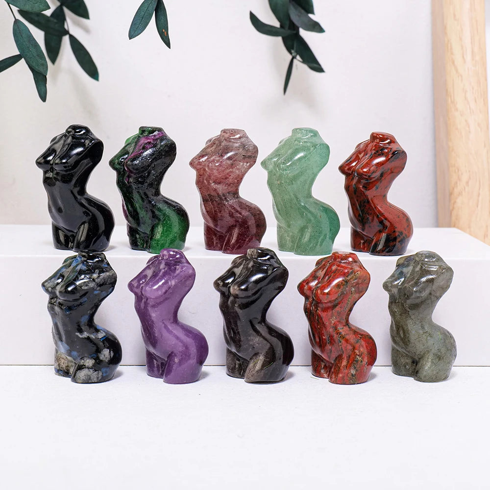 Una fila de nueve figuras de piedras curativas de cuarzo rosa natural en varios tonos de rosa, verde y marrón, exhibidas sobr