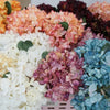A close-up display of various colored silk hydrangea stems in shades of peach, pink, white, and blue.