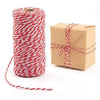 A roll of red and white striped cotton baker's twine ribbon with a loose end next to a cardboard gift box.