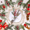 A festive arrangement featuring frosted pine needles, red berries, and gold accents on a white plate.