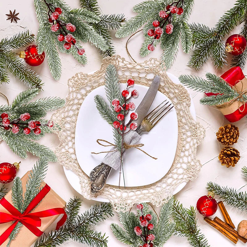 A festive arrangement featuring frosted pine needles, red berries, and gold accents on a white plate.