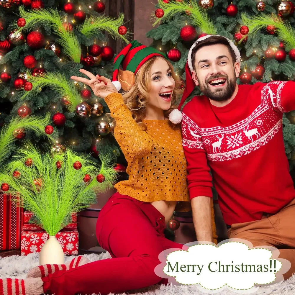 A smiling couple in festive red clothing posing with a decorated Christmas tree.