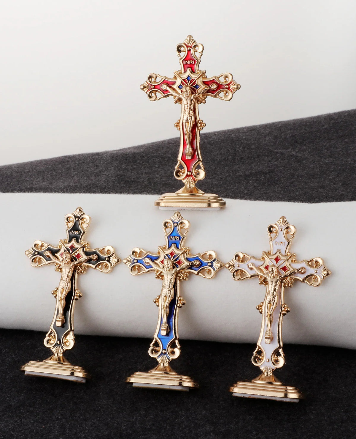 Three gold metal crucifix desk crosses with self-adhesive bases displayed on a dark surface.