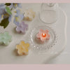 A collection of handmade soy wax flower tea light candles in various pastel shades arranged on a white plate.