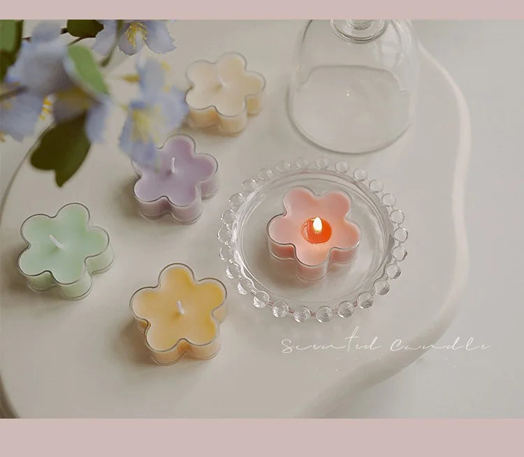 A collection of handmade soy wax flower tea light candles in various pastel shades arranged on a white plate.