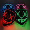A pair of glow-in-the-dark LED purge masks with neon wire details illuminated against a dark background.