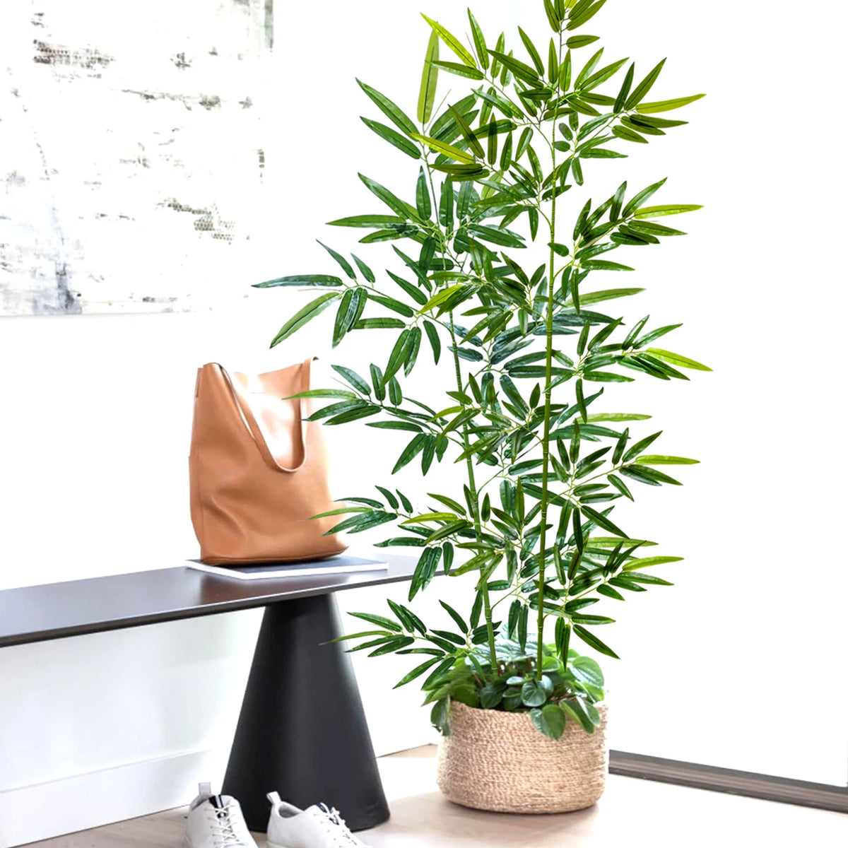 An artificial bamboo branch with green leaves is displayed in a woven pot on a dark table.