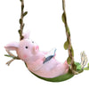 Pink resin climbing monkey figurine with a book resting on its body, hanging from a vine.
