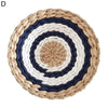 Round woven straw wall decor hanging featuring concentric rings of white, dark blue, and natural straw colors.