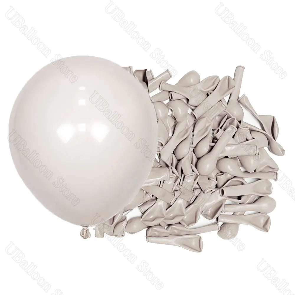 A white latex balloon next to a pile of light brown or beige latex balloons for decor.