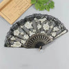 A black lace folding fan decorated with white roses and gold accents.