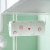 A roll of white paper towels decorated with small red and brown icons is held in a clear plastic holder.