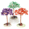 A display of three natural crystal money trees featuring green, purple, and orange-red crystals on copper wire stems.
