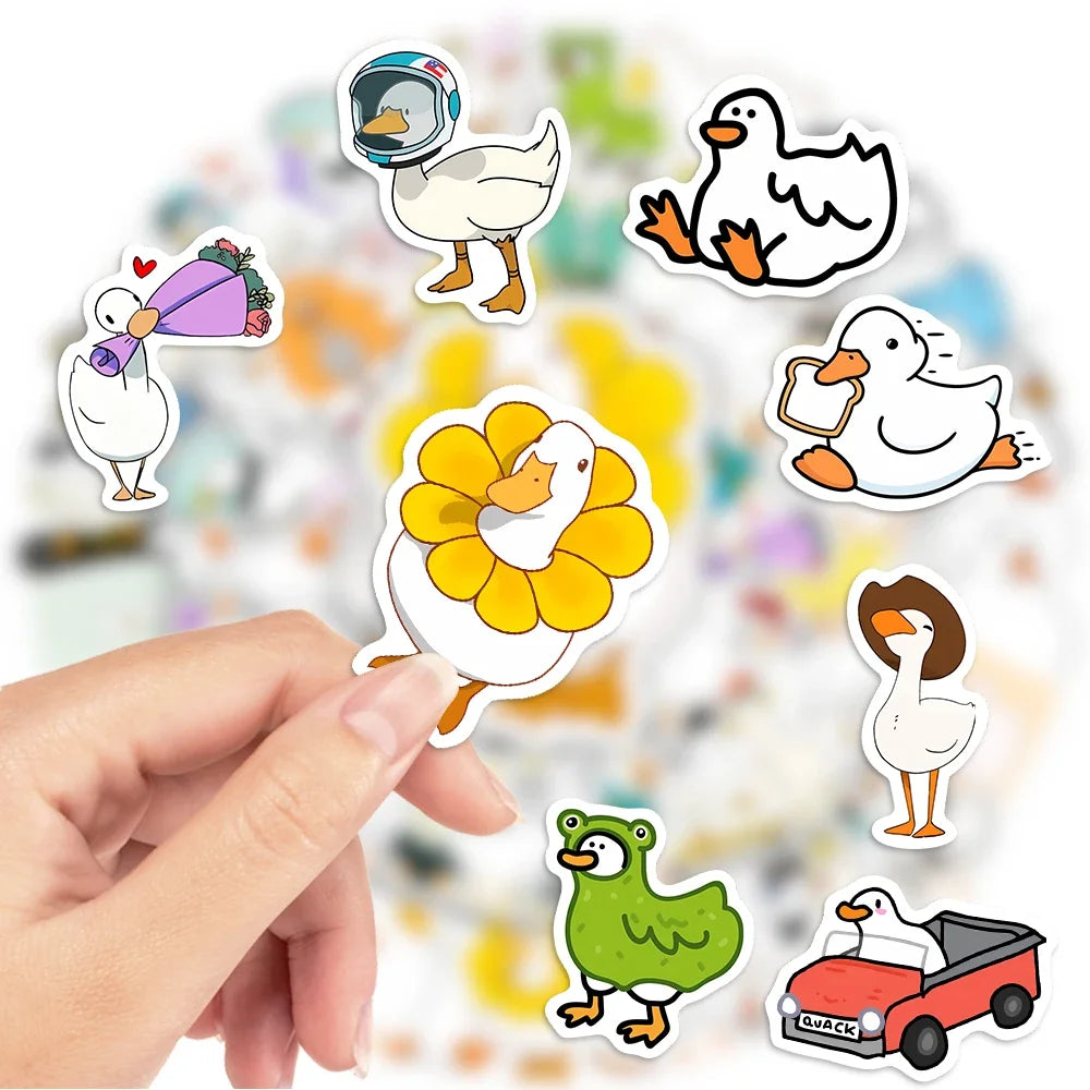 A hand is holding various funny cartoon duck and goose stickers on a blurred background.