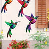 Set of four metal hummingbird wall decor featuring vibrant iridescent colors mounted on a white wall.