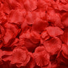 A close-up of vibrant red artificial silk rose petals scattered in a pile.