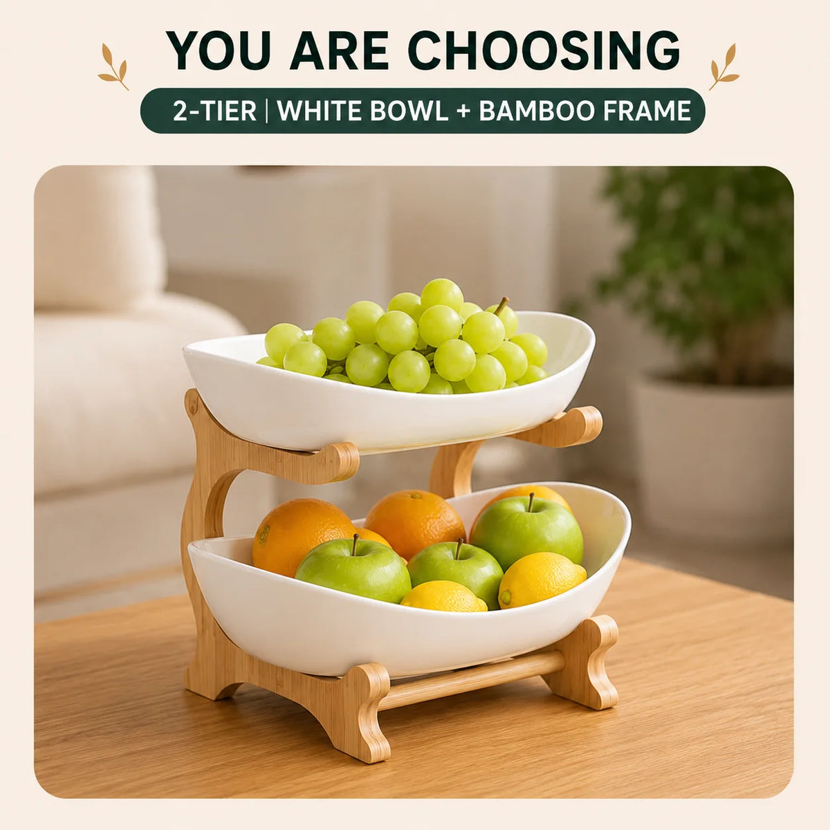 A two-tier fruit basket stand featuring a white bowl and bamboo frame holding green grapes and yellow apples.