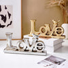 Retro gold and silver foil resin letters spelling LOVE displayed on a white surface.