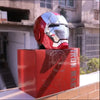 A red Iron Man helmet is displayed on a box, featuring a metallic finish and visible design details.