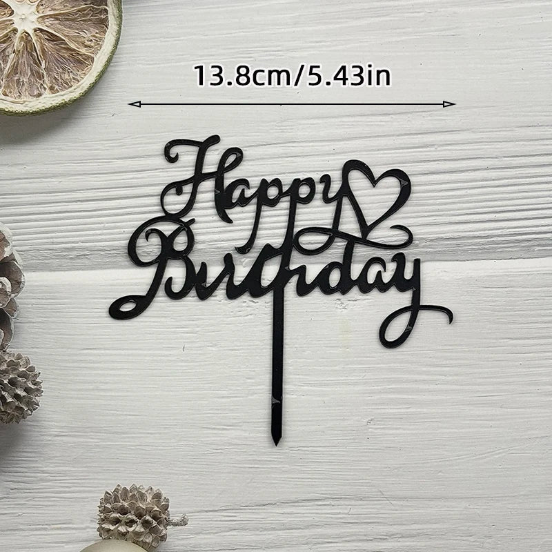 Elegant black acrylic cake topper set with Happy Birthday script and a heart design on a white wooden background.