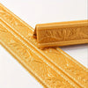 Gold self-adhesive foam wall trim strips with embossed floral patterns shown in close-up.