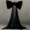 A black satin bow with a long, sheer tulle drape hanging down.