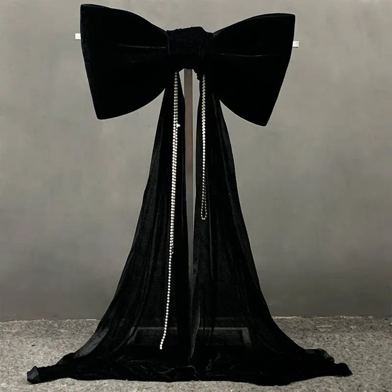 A black satin bow with a long, sheer tulle drape hanging down.