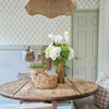A bouquet of white calla lily artificial flowers in a gold vase on a wooden table.