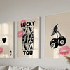 Three framed art prints featuring the text LUCKY YOU in various pink and black typography styles