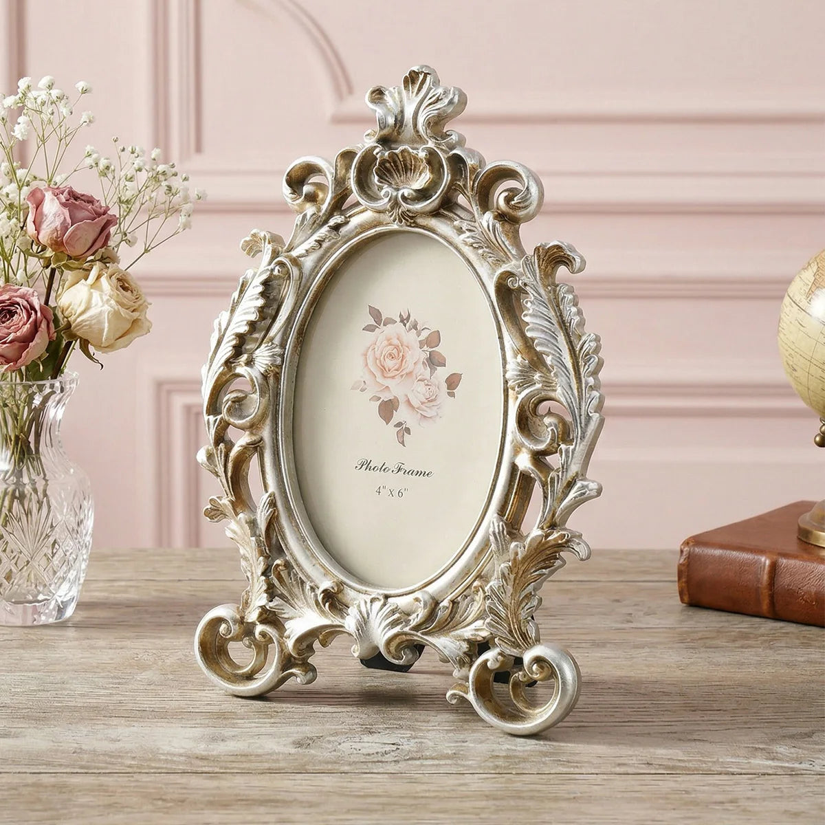 Vintage gold oval resin picture frame with ornate scrollwork displayed on a wooden surface.