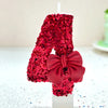 A large red glitter number candle shaped like an '8' decorated with a red bow for a birthday or celebration.