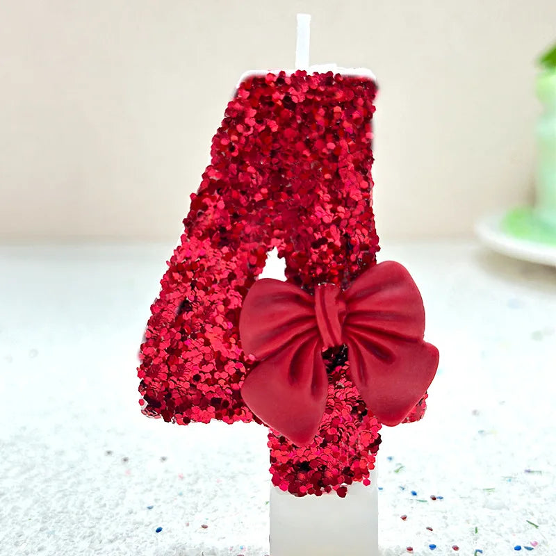 A large red glitter number candle shaped like an '8' decorated with a red bow for a birthday or celebration.
